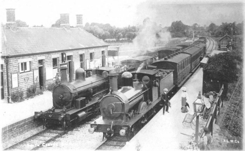 The down freight (left) waits at the up platform to allow the passenger train through